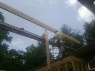 Carpenter setting a ridge beam over a new addition frame — Ice Dam Removal by Roofing Brothers in Byron
